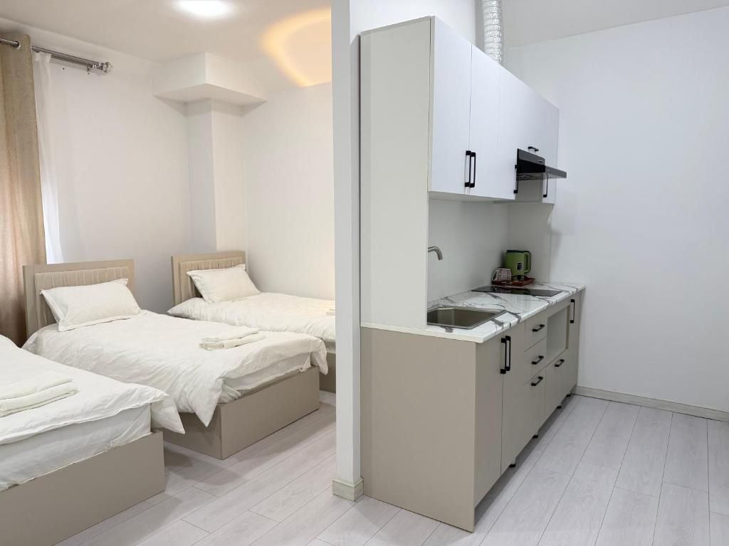 Un dormitorio con dos camas, un kitchenette y un baño con cortina de ducha.