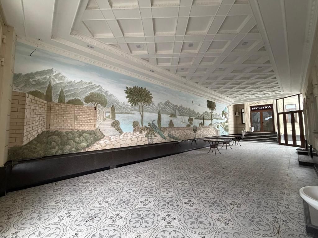 Un área de recepción con un mural, piso de baldosas y una escalera que sube a un nivel superior.