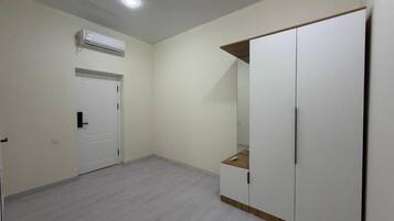 Una habitación con un armario blanco, una puerta y un equipo de aire acondicionado.