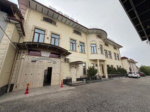 A hotel with a classic facade, a prominent entrance, and a parking area in front.