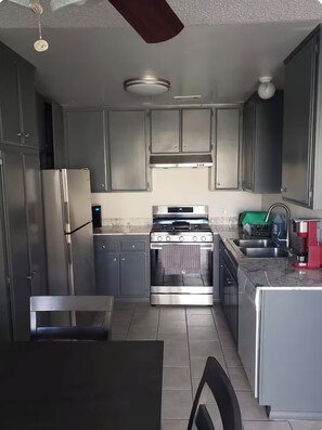 A kitchen with grey cabinets, a stainless steel refrigerator, a gas stove, and a sink. - Charming 2-bedroom condo with AC in lively Las Vegas (Las Vegas)