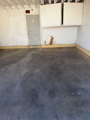 A clean, empty indoor space with a grey floor, a closed door, and a 'NO PARKING' sign above it. - Charming 2-bedroom condo with AC in lively Las Vegas (Las Vegas)