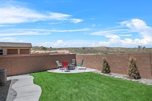 A backyard with a patio, outdoor furniture, and a view of a desert landscape.