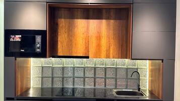 A modern kitchen with dark cabinetry, a wooden accent wall, and a tiled backsplash.