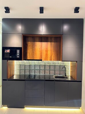 Een moderne keuken met donkere kastjes, een houten accentmuur en een betegelde spatwand.