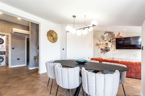 A modern dining area with a round table, grey upholstered chairs, and a contemporary light fixture. - A2 - luxury apartment near beach with big terrace and the sea view (Kaštel Gomilica)