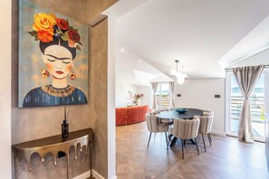 A modern dining area with a round table and chairs, a painting on the wall, and a view through large windows. - A2 - luxury apartment near beach with big terrace and the sea view (Kaštel Gomilica)