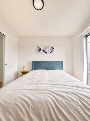 Een slaapkamer met een bed, een nachtkastje en een raam.