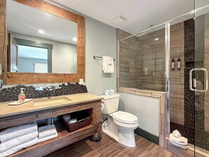 A modern bathroom with a wooden vanity, a toilet, a glass shower enclosure, and a large mirror. - New Listing - Plaza 339 — Updated 3BR Base Area Condo (Crested Butte)