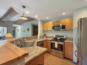 A modern kitchen with granite countertops, stainless steel appliances, wooden cabinets, and a pendant light. - New Listing - Plaza 339 — Updated 3BR Base Area Condo (Crested Butte)
