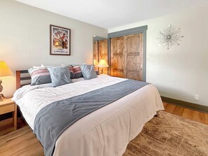 A bedroom with a bed, bedside lamps, a wooden wardrobe, and a wall decoration. - New Listing - Plaza 339 — Updated 3BR Base Area Condo (Crested Butte)