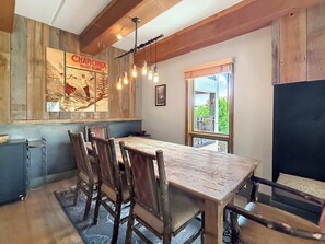 A rustic dining area with a wooden table and chairs, a hanging light fixture, and a poster on the wall. - New Listing - Plaza 339 — Updated 3BR Base Area Condo (Crested Butte)