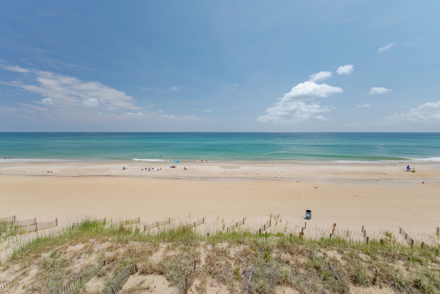 A beach with a sandy shore, a wooden fence, and a clear sky.