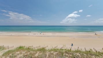 A beach with a sandy shore, a wooden fence, and a clear sky.