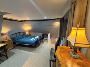 Ein Schlafzimmer mit einem Bett, Nachttischen, einem Schreibtisch und einer Lampe.