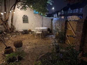 Ein Garten mit Tisch und Stühlen, einem Blumentopf und einem Holzzaun.