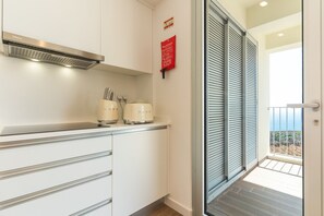 A modern kitchen with white cabinets, a stainless steel range hood, and two white appliances on the counter. - Azure Oasis Madeira by Atlantic Holiday (Câmara de Lobos)