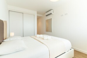 A hotel room with a bed, a wardrobe, an air conditioning unit, a mirror, and a wall socket. - Azure Oasis Madeira by Atlantic Holiday (Câmara de Lobos)