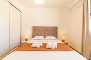 Une chambre d’hôtel avec un lit, deux lampes de chevet, une tête de lit et deux serviettes sur le lit.