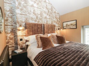 Ein Schlafzimmer mit einem großen Bett, zwei Nachttischlampen, einem gerahmten Bild an der Wand und einer Heizung.