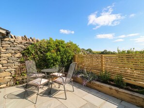 Eine Terrasse mit Steinmauern, einem Holzzaun und einem Tisch mit Stühlen.