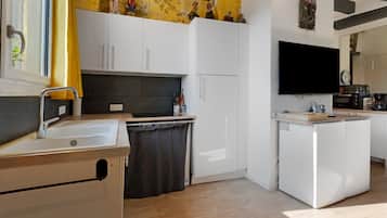 Eine moderne Küche mit weißen Schränken, einem Einbauofen, einer Spüle und einem an der Wand befestigten Flachbildfernseher.
