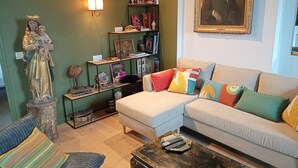 En stue med en statue, en sofa, et sofabord og en bogreol.