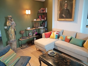 Een woonkamer met een beeld, een bank, een salontafel en een boekenkast.
