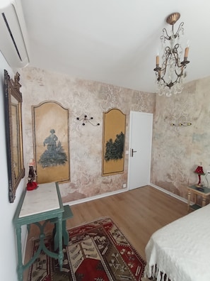 Een kamer met een bed, een bureau, een spiegel en een deur.