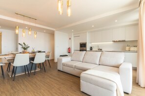 Ein modernes Wohnzimmer mit Sofa, Essbereich und Küche.