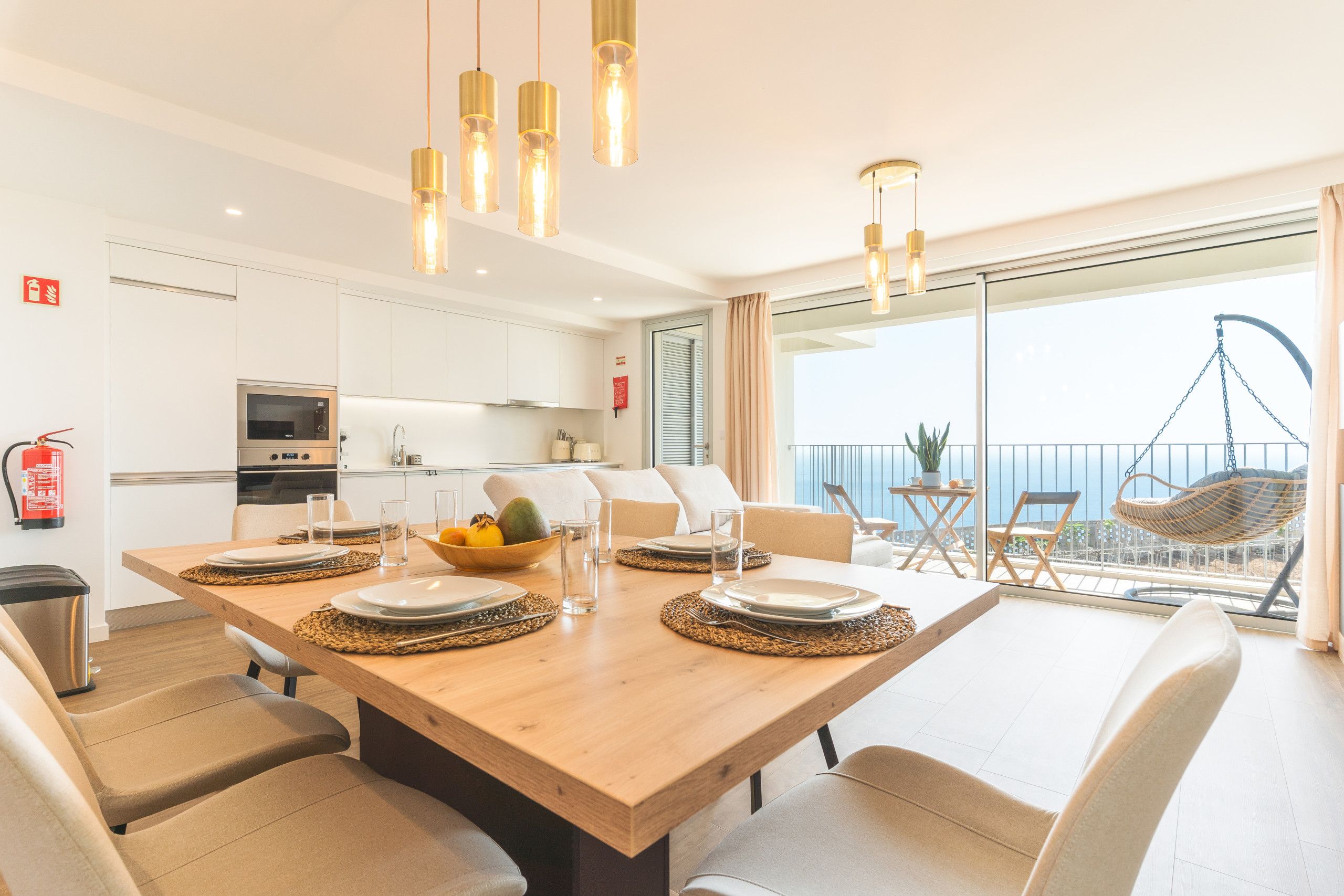 A modern dining area with a wooden table set for four, surrounded by chairs.