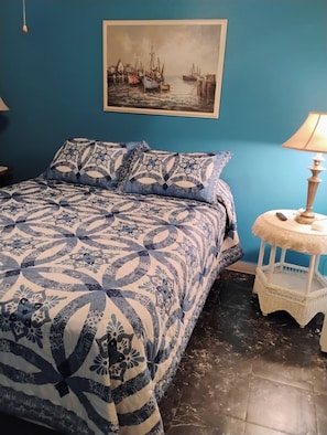 A bedroom with a bed, a nightstand, a lamp, and a painting on the wall. - Comfortable Cozy 1 bedroom Cottage in quaint Port Orange (Port Orange)
