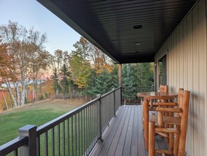 Una terraza de madera con barandilla, una mesa y sillas.