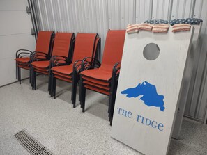 A row of orange chairs with black metal frames, a white podium with a blue silhouette and text, and a corrugated metal wall in the background. - The Ridge! Amazing view of Lake Superior, close to downtown & room for all (Grand Marais)
