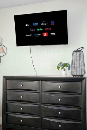 A flat-screen TV mounted on a wall displaying various streaming service logos. - Elegant 2BR Apartment right by Cowboys Stadium! (Arlington)