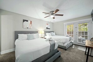 A bedroom with two beds, a ceiling fan, artwork on the walls, and a sliding glass door to the outside. - Elegant 2BR Apartment right by Cowboys Stadium! (Arlington)