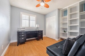 Ein Zimmer mit einem dunklen Holztisch, einem weißen Kleiderschrank und einem schwarzen Sofa.