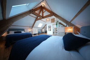 An attic bedroom with two beds, wooden beams, a skylight, and a hanging light fixture. - The Kordokov vacation rental—a renovated old farmhouse near the sea, set in the heart of a stable (Tréméreuc)