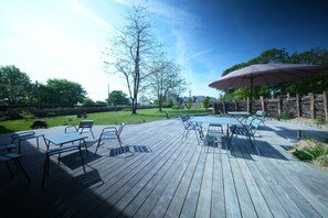A wooden deck with outdoor furniture and a large umbrella. - The Kordokov vacation rental—a renovated old farmhouse near the sea, set in the heart of a stable (Tréméreuc)