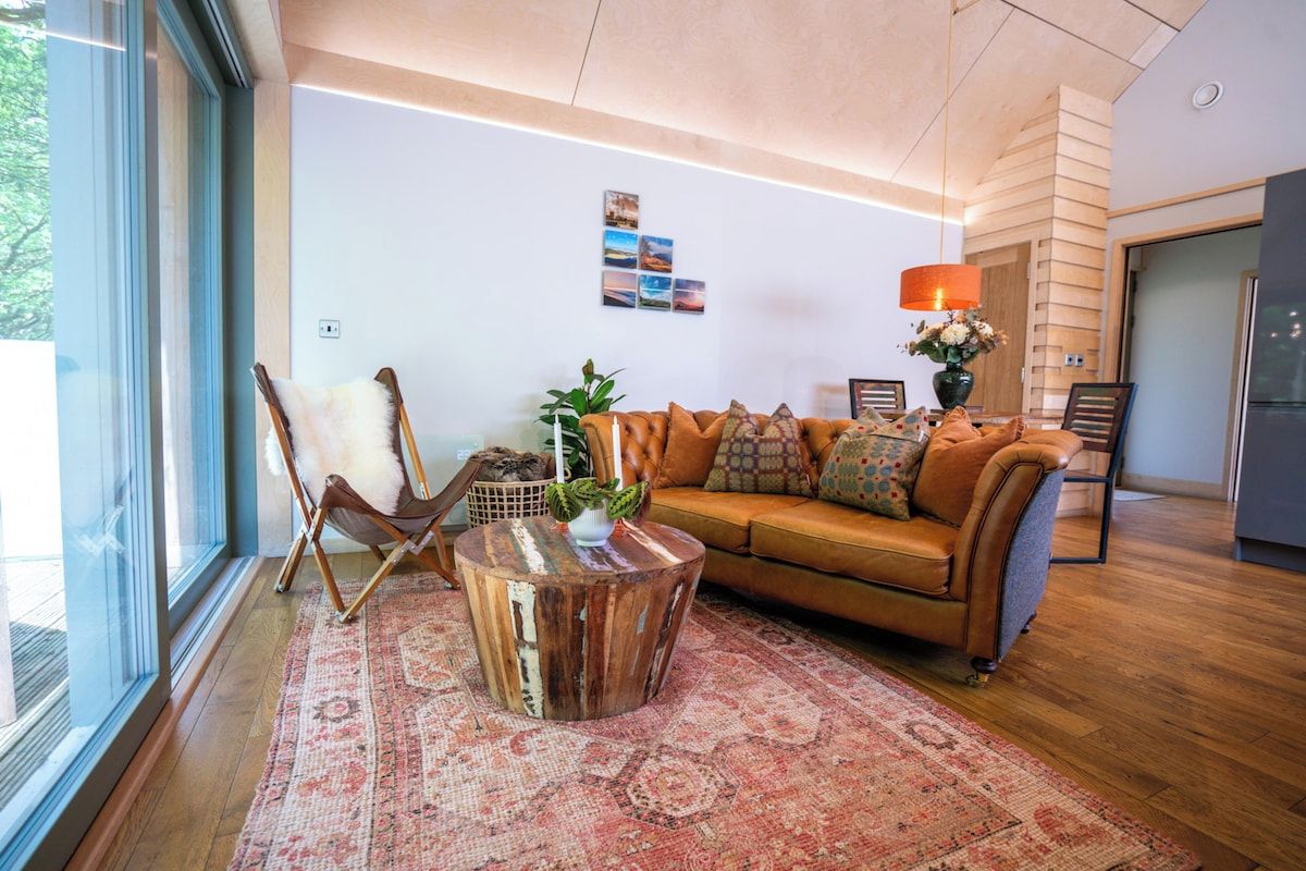 Una sala de estar moderna con un sofá de cuero, una mesa de centro de madera y un ventanal que proporciona luz natural.
