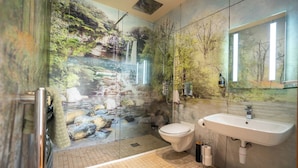 Een badkamer met een douchecabine van glas, een toilet en een wastafel.
