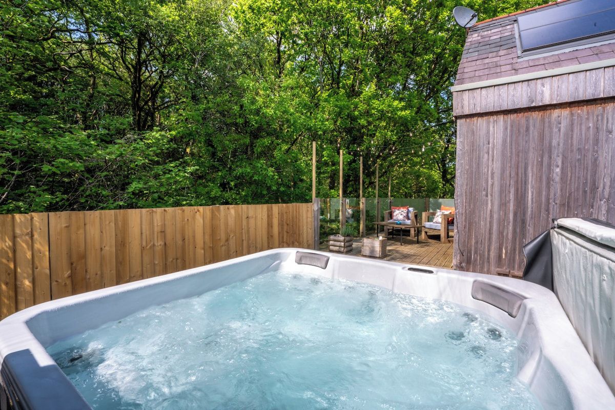 Ein Whirlpool, umgeben von einem Holenzaun und Bäumen.