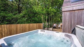 Un jacuzzi rodeado por una valla de madera y árboles.