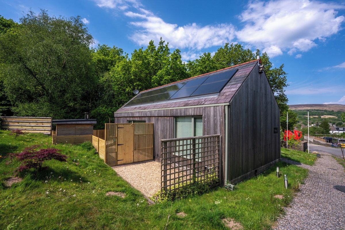 A wooden cabin with a sloped roof and a small porch area.