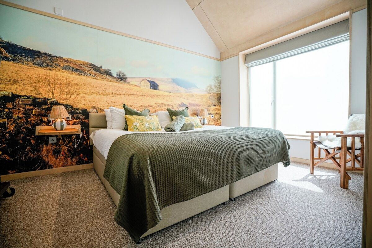 A bedroom with a large bed, a nightstand, a lamp, and a chair.