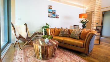 A living room with a leather sofa, a wooden coffee table, a patterned rug, a chair, and a wall with a picture.