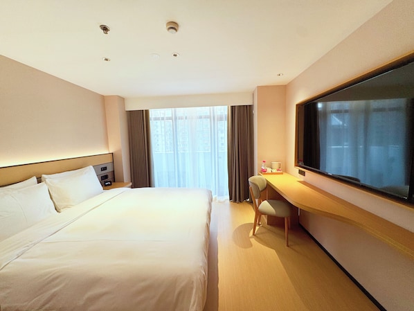 Une chambre d’hôtel équipée d’un lit, d’un bureau, d’une chaise, d’une télévision et d’une fenêtre avec des rideaux.