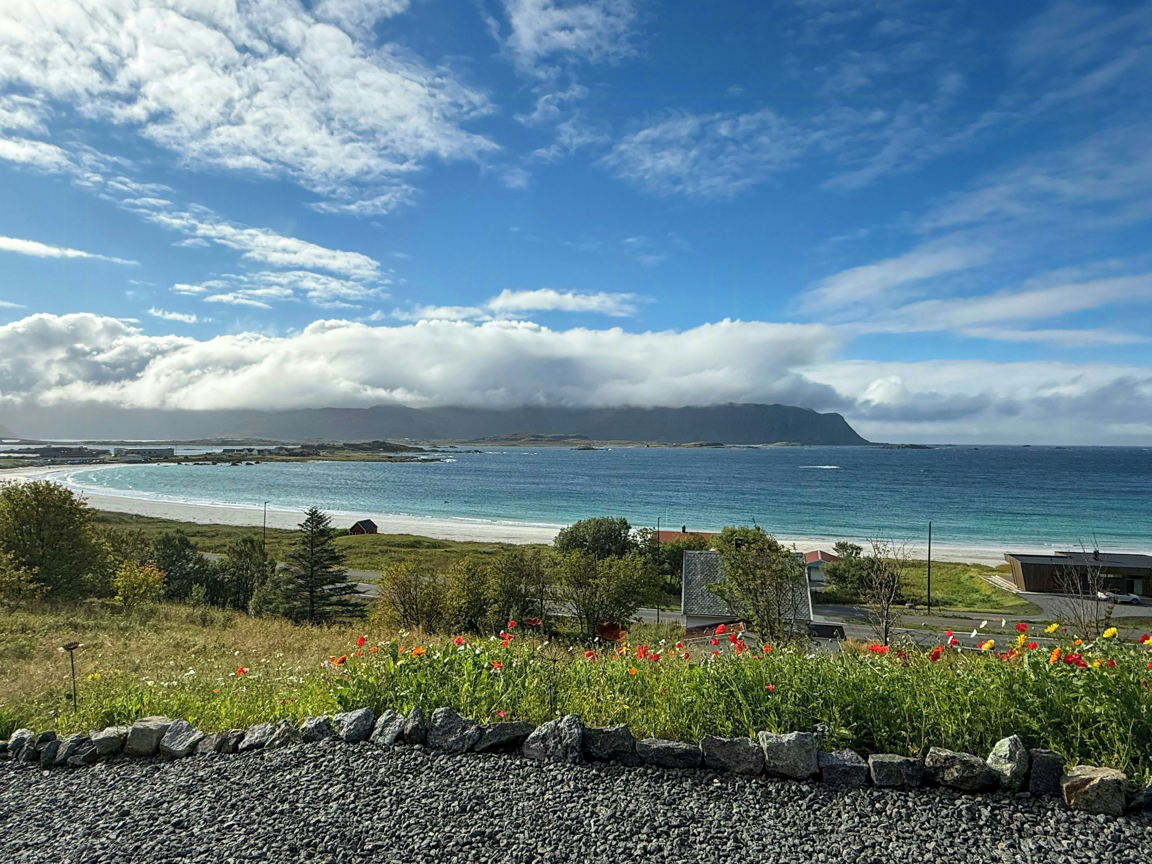 A coastal landscape with a clear sky, a beach, and a mountain in the distance.