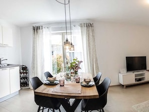A modern kitchen with a dining area, a TV, and a window with curtains. - Claudia's Seeherz (Wasserburg am Bodensee)