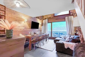 Ein Holzinnenraum mit Essbereich, einer Couch und einem großen Fenster mit Blick auf ein Gewässer.